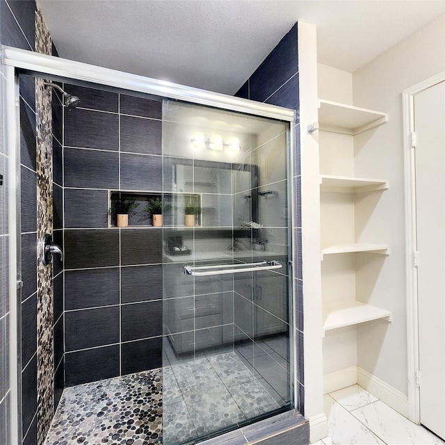 full bathroom with a textured ceiling, marble finish floor, a stall shower, and baseboards