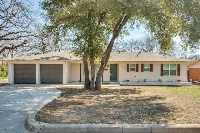 single story home with driveway, brick siding, and an attached garage