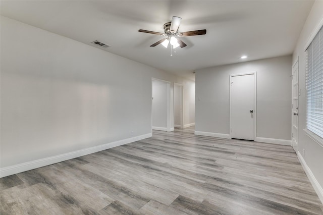 empty room with light wood finished floors, baseboards, visible vents, and ceiling fan