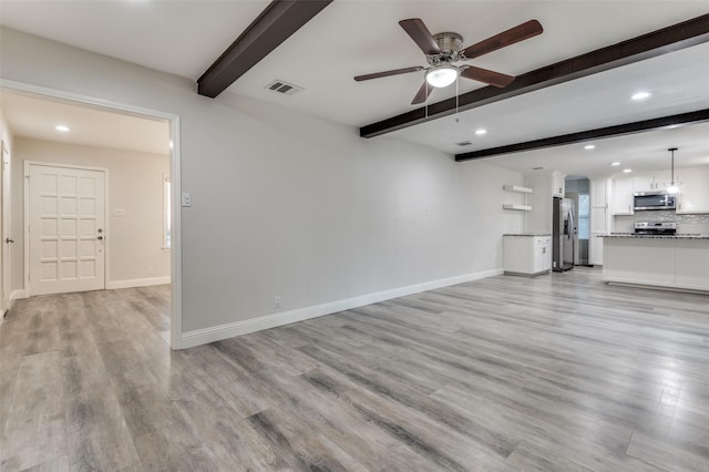 unfurnished living room with visible vents, beamed ceiling, light wood-style flooring, and baseboards