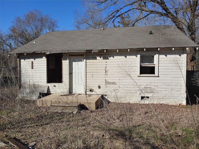 rear view of house with roof with shingles and crawl space