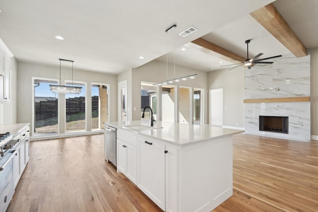 kitchen with a premium fireplace, a sink, visible vents, light wood-style floors, and stainless steel dishwasher