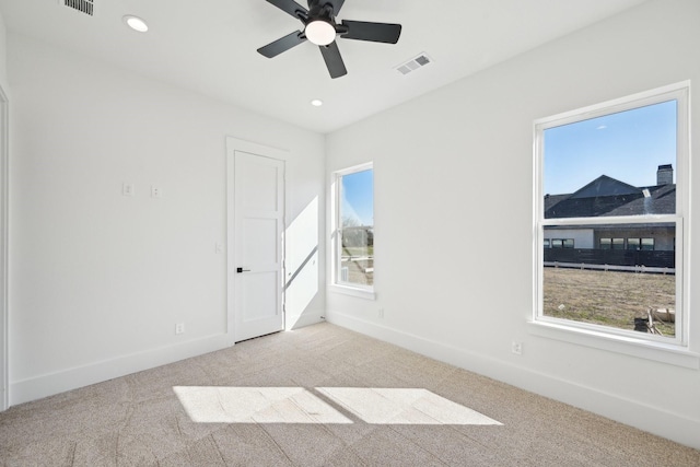 spare room featuring carpet floors, visible vents, and baseboards