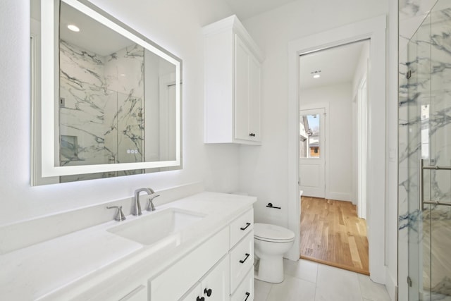 full bath with a marble finish shower, recessed lighting, toilet, vanity, and tile patterned flooring