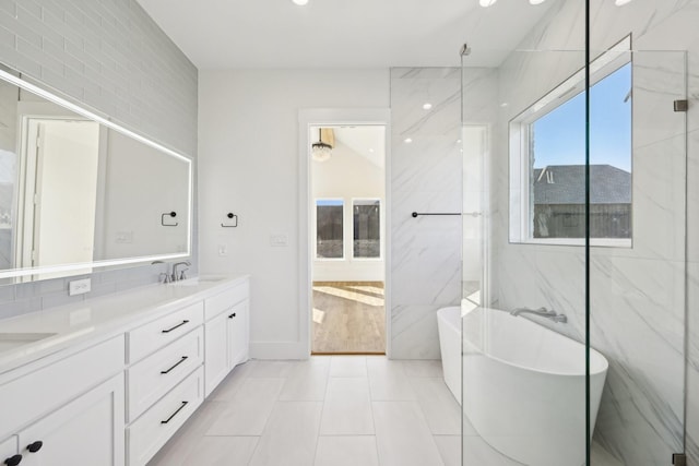 bathroom featuring a freestanding tub, a sink, tile walls, and double vanity