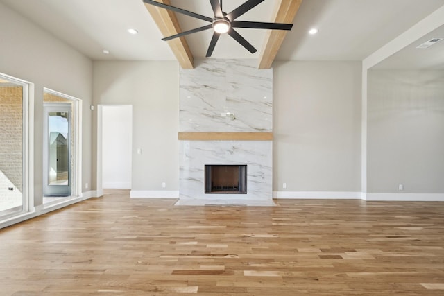 unfurnished living room featuring light wood-style floors, visible vents, beam ceiling, and a high end fireplace