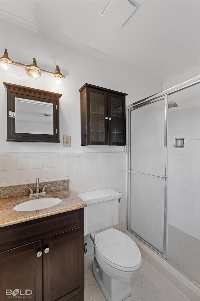 bathroom with toilet, vanity, a shower stall, and tile walls