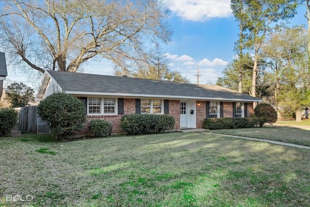 ranch-style house featuring brick siding, fence, and a front lawn