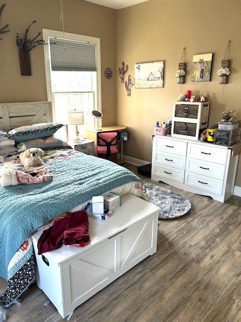 bedroom with dark wood-type flooring and baseboards