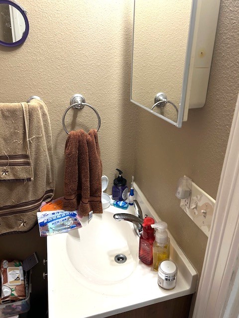 bathroom with a textured wall and vanity