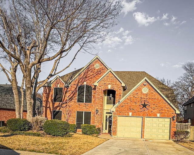 traditional-style home with an attached garage, roof with shingles, concrete driveway, and brick siding