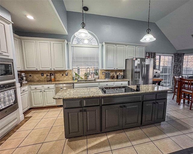 kitchen featuring stainless steel appliances, a center island, white cabinets, and a sink