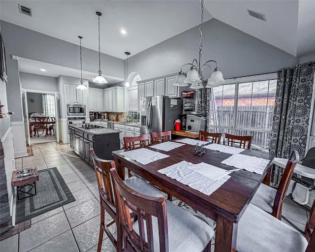 dining space with high vaulted ceiling, a chandelier, and visible vents