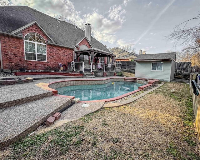 pool with a fenced backyard, an outbuilding, a patio, and a gazebo