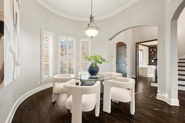 dining room with ornamental molding, arched walkways, dark wood-style flooring, and baseboards