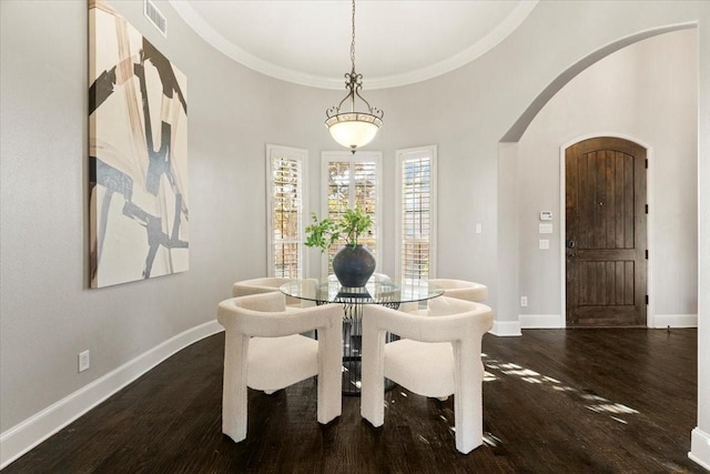 dining area featuring arched walkways, visible vents, baseboards, and wood finished floors