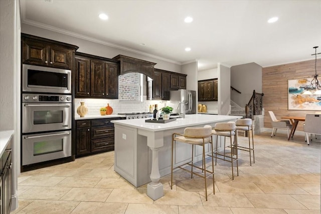 kitchen featuring decorative backsplash, stainless steel appliances, light countertops, and a kitchen breakfast bar