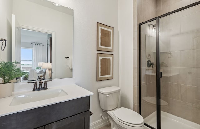 bathroom featuring toilet, a stall shower, and vanity