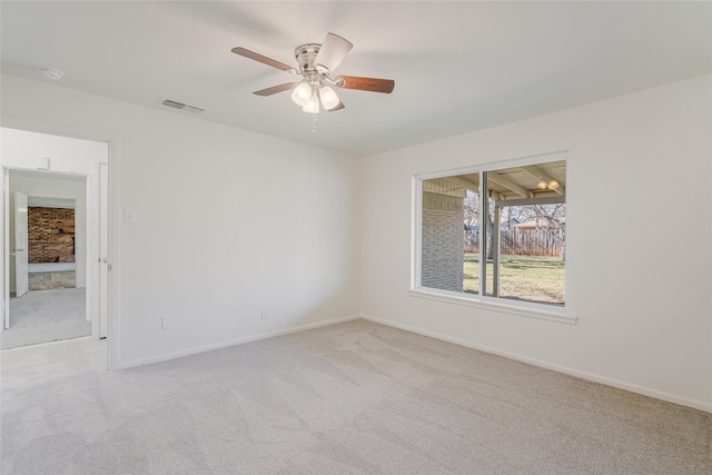 empty room featuring light carpet, a ceiling fan, visible vents, and baseboards