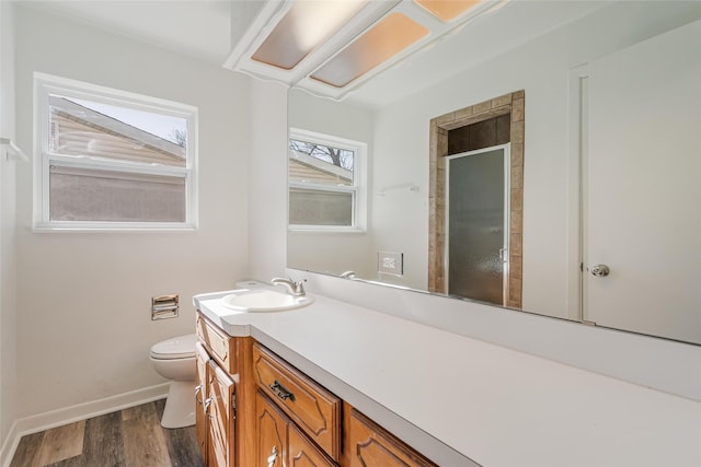 bathroom with toilet, wood finished floors, vanity, baseboards, and a stall shower