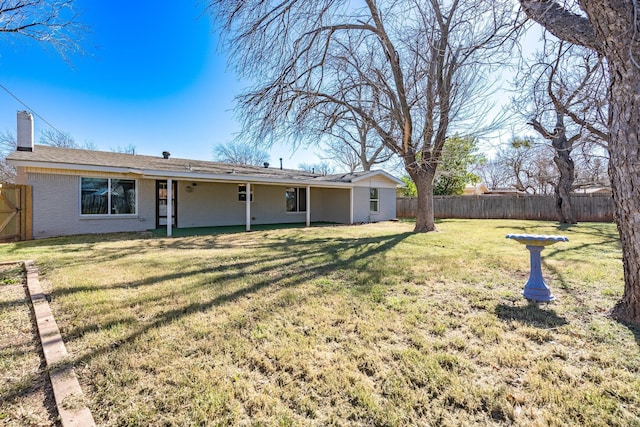 rear view of property with brick siding, a lawn, and fence