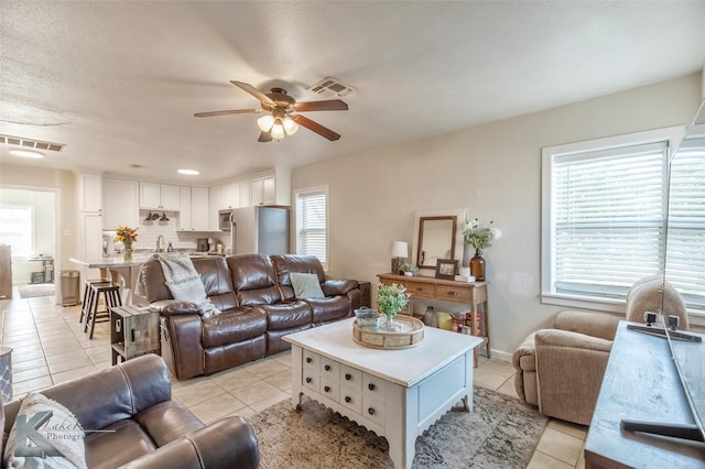 living area with visible vents, ceiling fan, baseboards, and light tile patterned floors