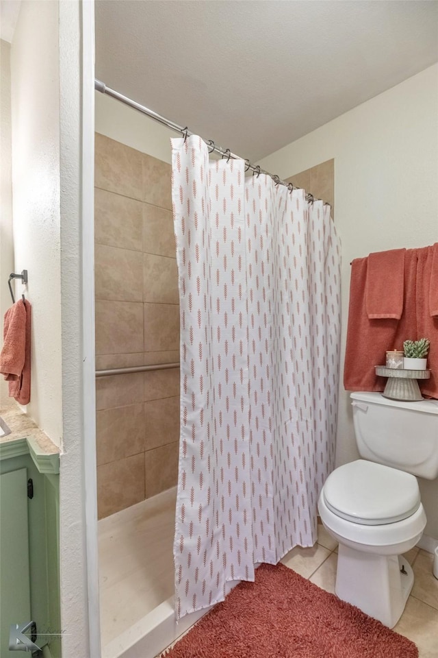 full bathroom with tiled shower, toilet, and tile patterned floors