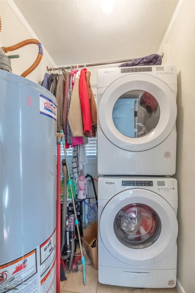 laundry room featuring stacked washer and dryer, gas water heater, a textured ceiling, and laundry area