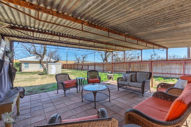 view of patio / terrace with a fenced backyard, a storage unit, outdoor lounge area, and an outbuilding