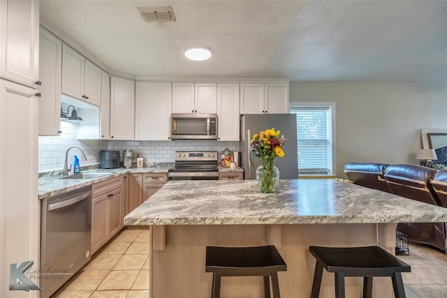 kitchen featuring appliances with stainless steel finishes, a sink, visible vents, and decorative backsplash