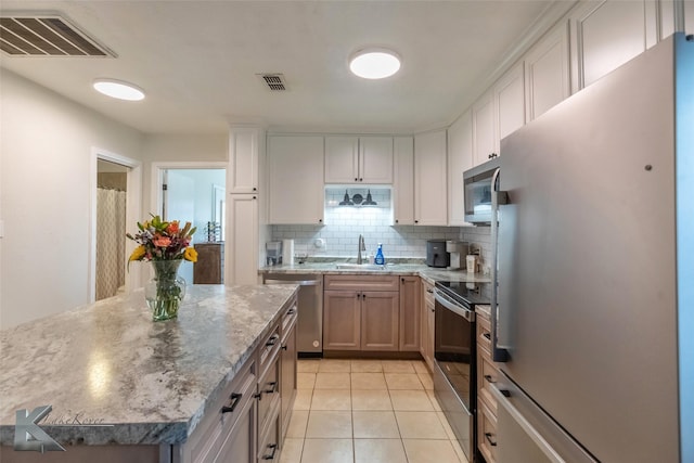 kitchen featuring stainless steel appliances, tasteful backsplash, visible vents, light tile patterned flooring, and a sink