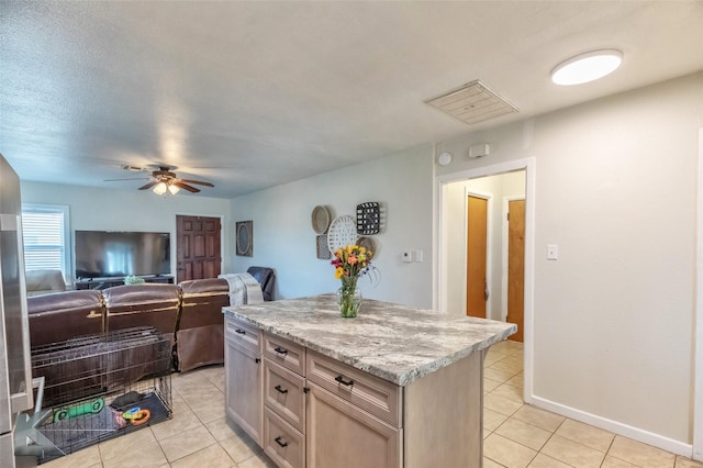 kitchen featuring light tile patterned floors, visible vents, ceiling fan, a kitchen island, and open floor plan