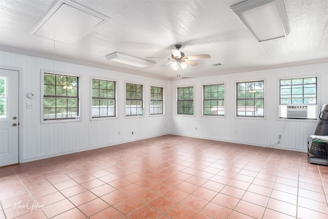 unfurnished sunroom featuring ceiling fan, plenty of natural light, cooling unit, and visible vents