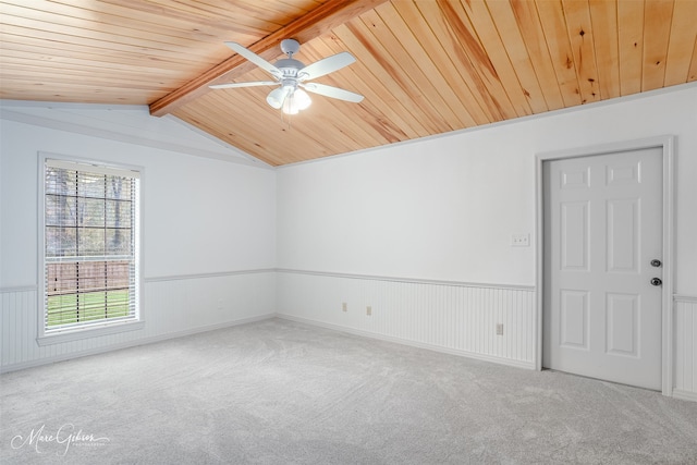 carpeted empty room featuring a wainscoted wall, ceiling fan, wooden ceiling, and vaulted ceiling with beams