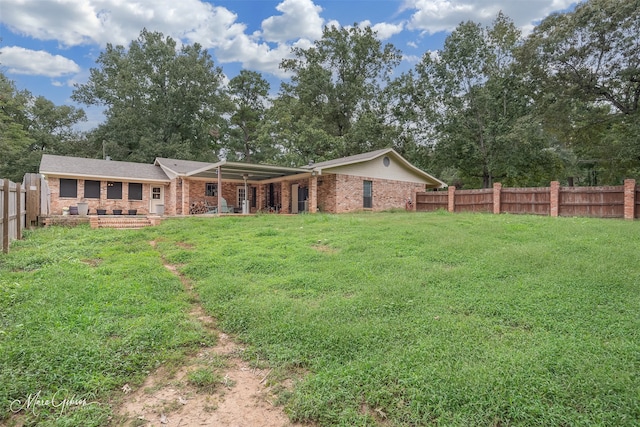 rear view of property featuring brick siding, a lawn, and fence private yard