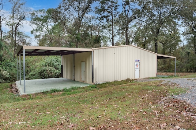 view of outdoor structure with a carport, driveway, and an outdoor structure