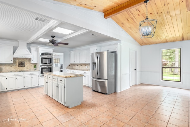 kitchen featuring a wainscoted wall, custom exhaust hood, stainless steel appliances, wood ceiling, and light tile patterned flooring