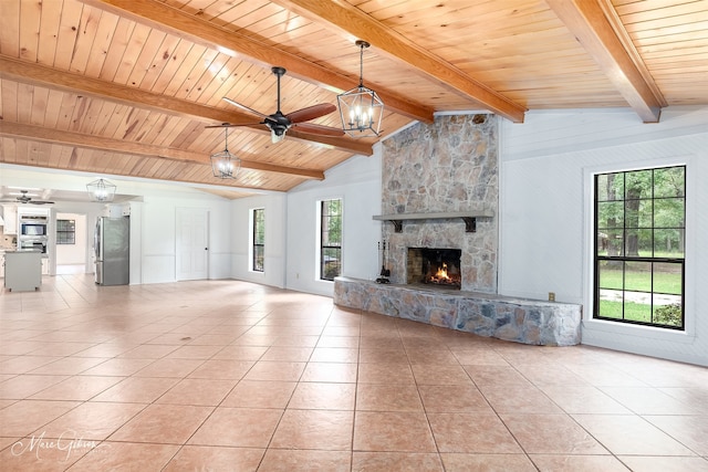 unfurnished living room featuring ceiling fan with notable chandelier, a stone fireplace, and light tile patterned floors