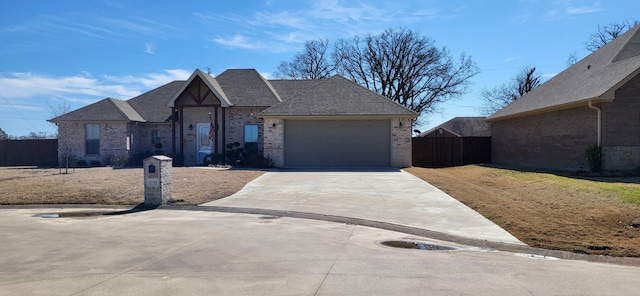 view of front facade featuring brick siding, roof with shingles, concrete driveway, an attached garage, and fence