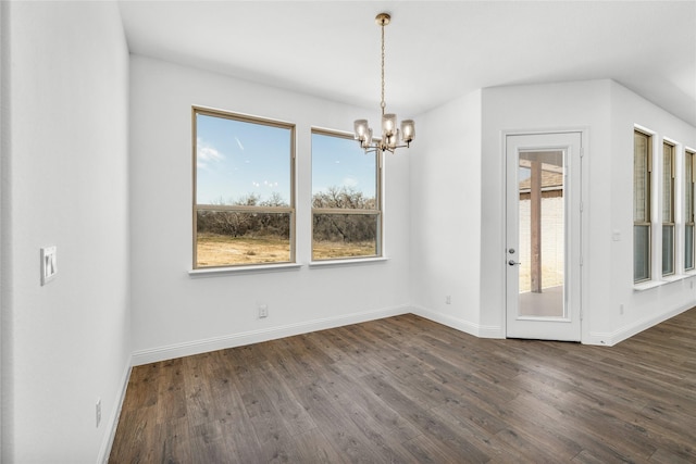 unfurnished dining area with a chandelier, dark wood finished floors, and baseboards