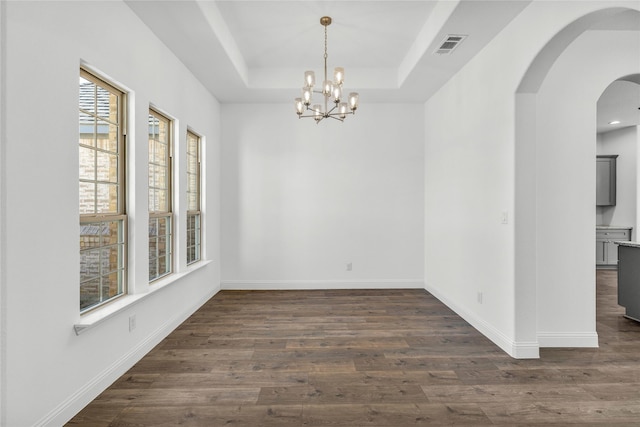 unfurnished dining area with a tray ceiling, dark wood finished floors, and baseboards