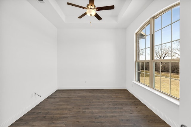 unfurnished room with dark wood-style floors, baseboards, and a raised ceiling