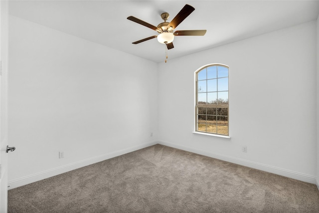 carpeted empty room featuring a ceiling fan and baseboards