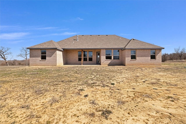 back of property featuring a patio area, brick siding, and roof with shingles