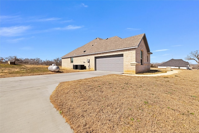 view of home's exterior with driveway, a garage, a shingled roof, a lawn, and brick siding