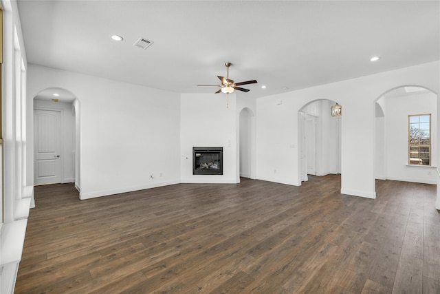 unfurnished living room with recessed lighting, visible vents, dark wood-type flooring, and a glass covered fireplace