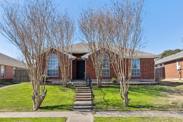 view of front facade with a shingled roof, brick siding, fence, and a front lawn