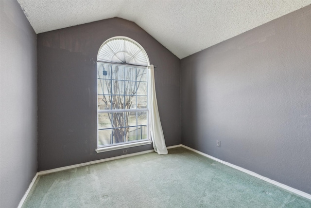 carpeted spare room featuring lofted ceiling, a textured ceiling, and baseboards