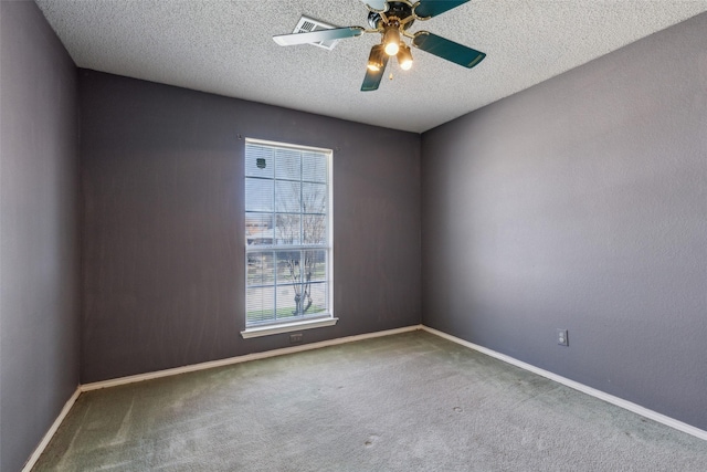 carpeted spare room with a textured ceiling, baseboards, and a ceiling fan