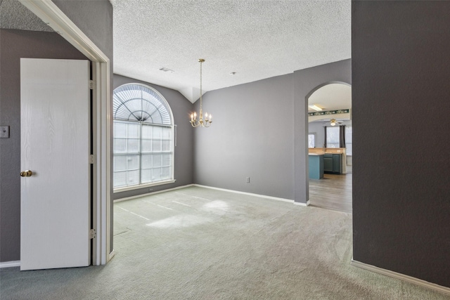 empty room featuring baseboards, arched walkways, an inviting chandelier, a textured ceiling, and carpet flooring